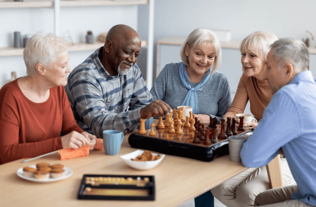 A group of senior sitting next to each other at a table playing a game of chess in a senior living community.