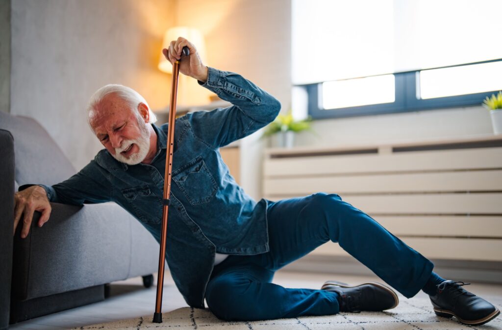 older man falls and braces himself back up using his cane.