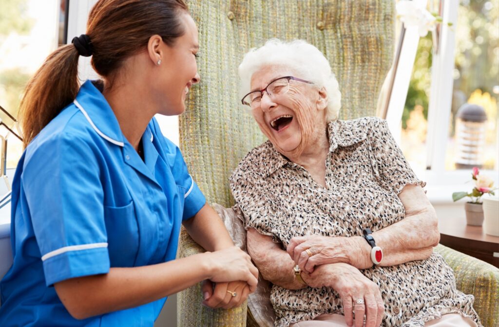 A senior woman in memory care laughing with her caregiver.