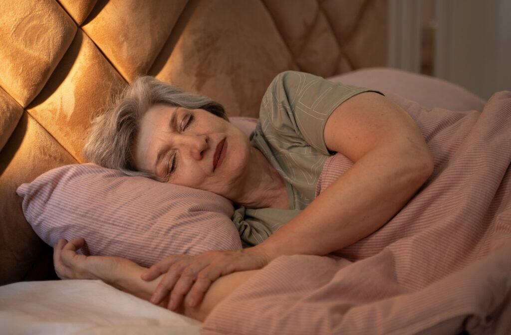 an elderly woman sleeping peacefully with her head on the pillow and a dim light in the background