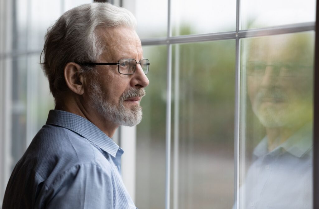 Senior with glasses looking off into the distance out the window.