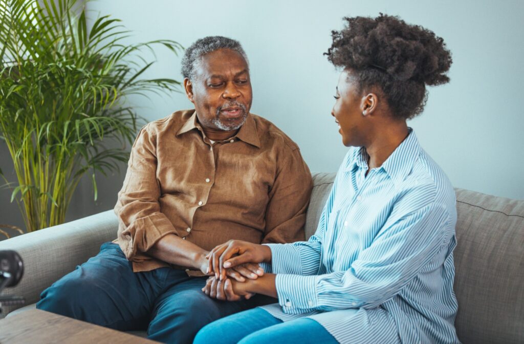 An adult child listening to their senior parent talk while actively listening and holding their hands.