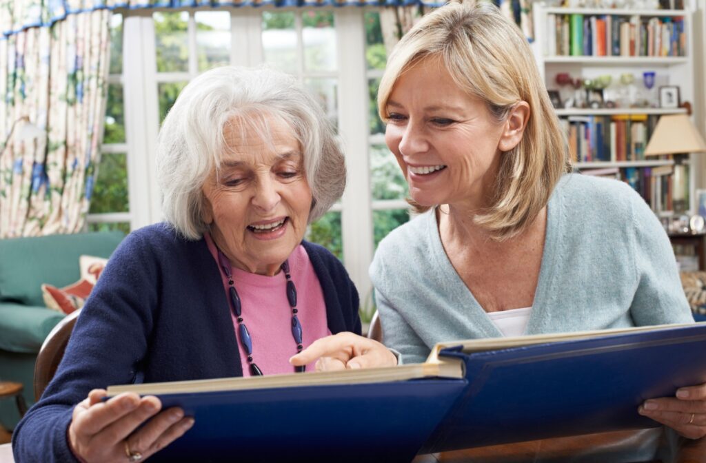 A senior and their loved one reminiscing over a photo album together at a memory care community