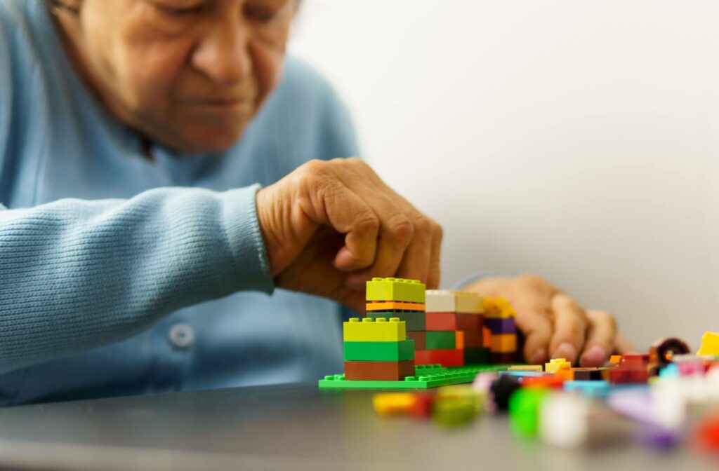 A senior in memory care plays with LEGO bricks as a method of occupational therapy to help with cognitive functioning