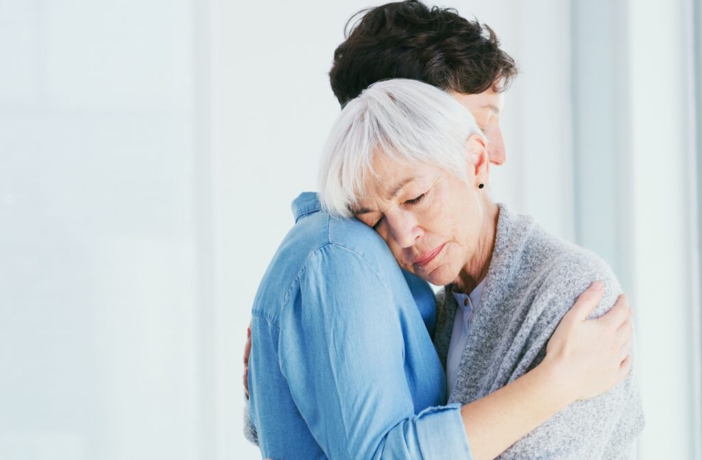 An adult child hugs their older parent at home after a serious discussion about a potential move to memory care