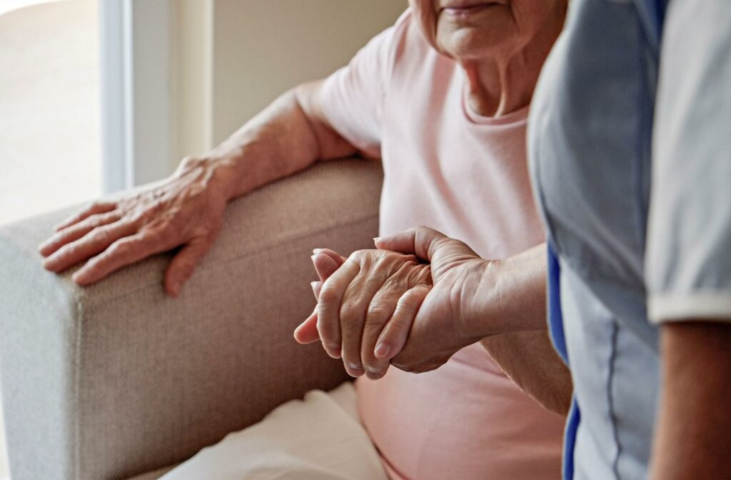 carer holding the hand of a senior in support